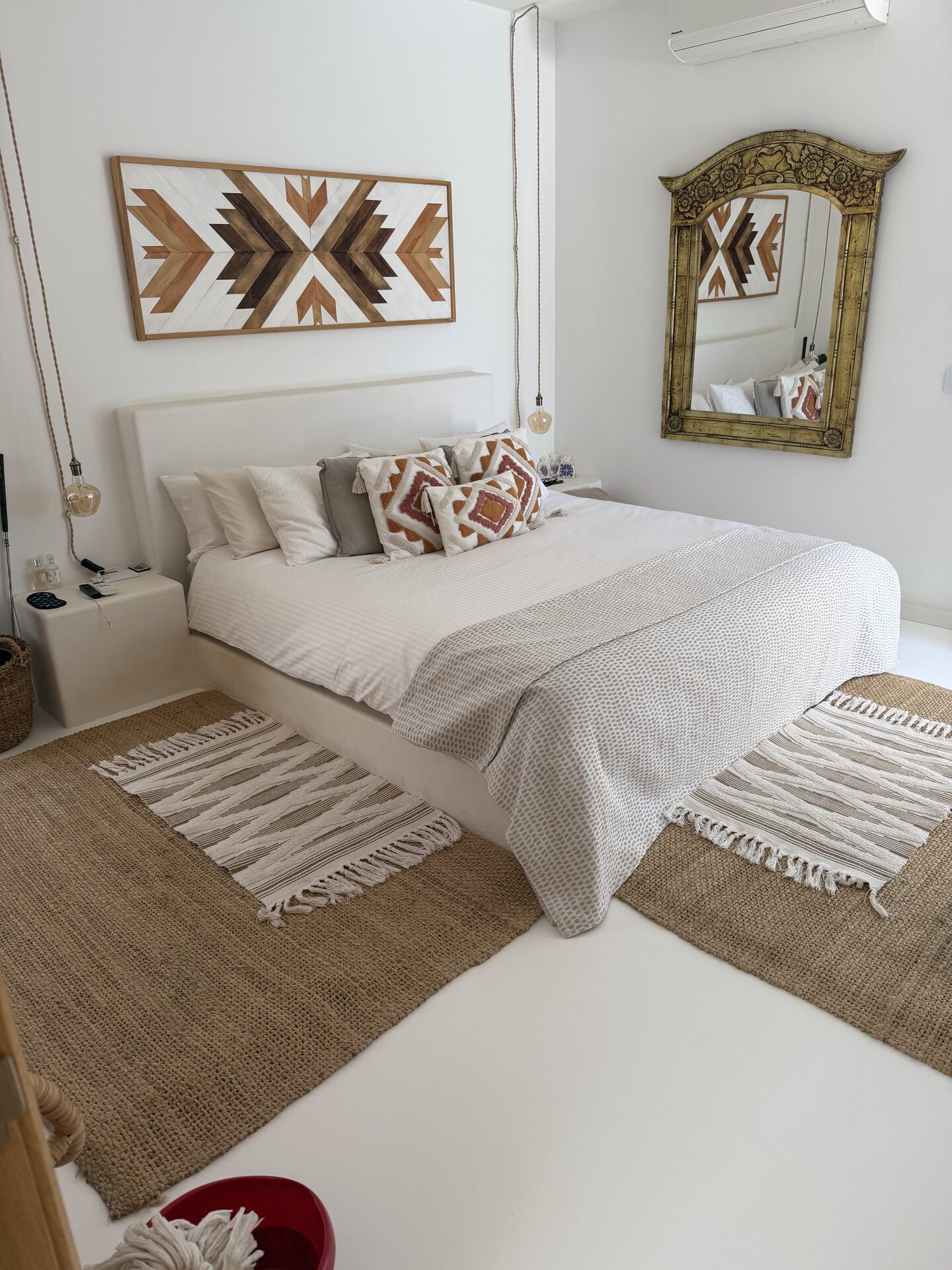Chambre principale avec coussins terracotta et miroir doré