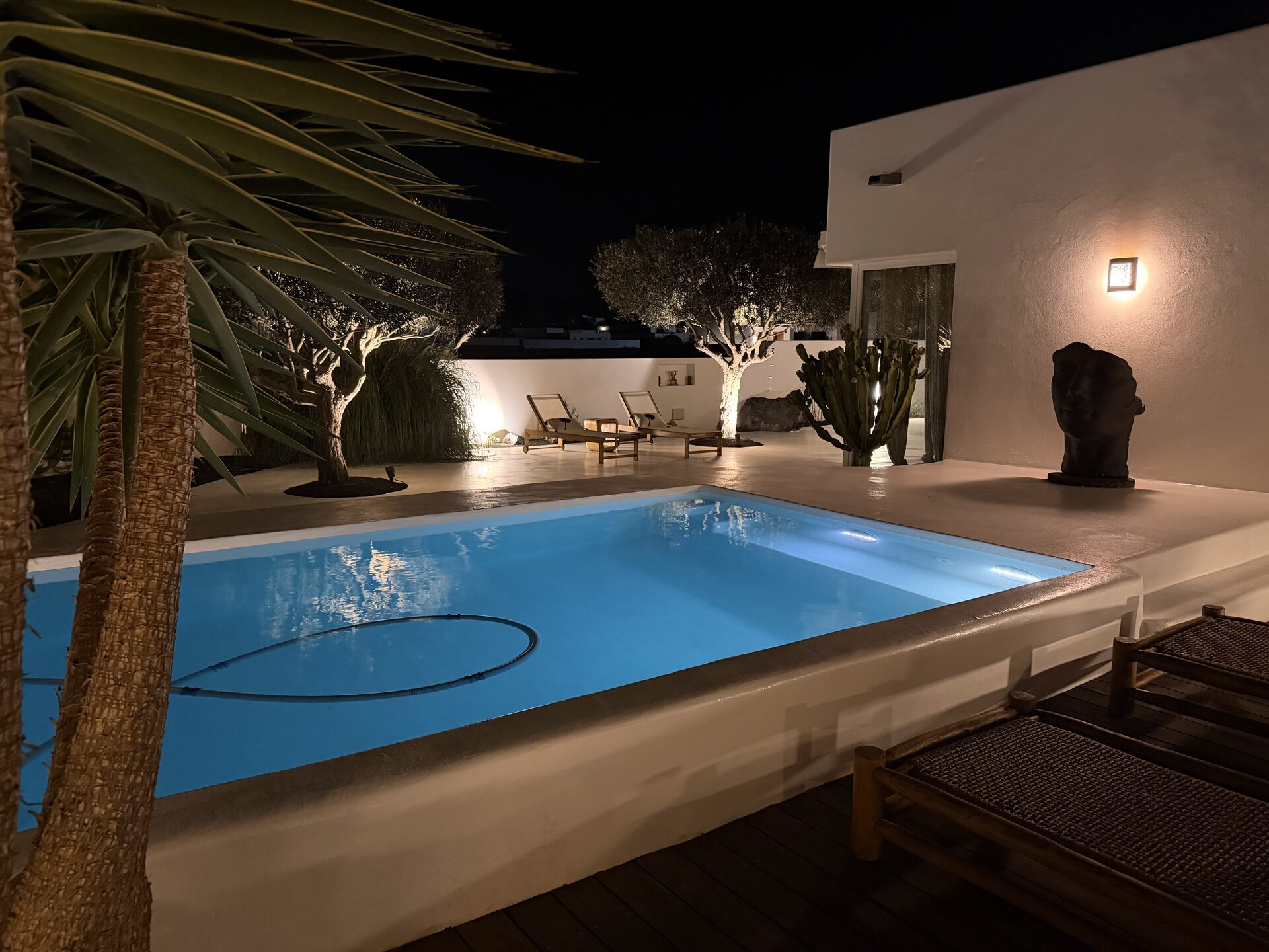 Piscine illuminée la nuit avec sculpture
